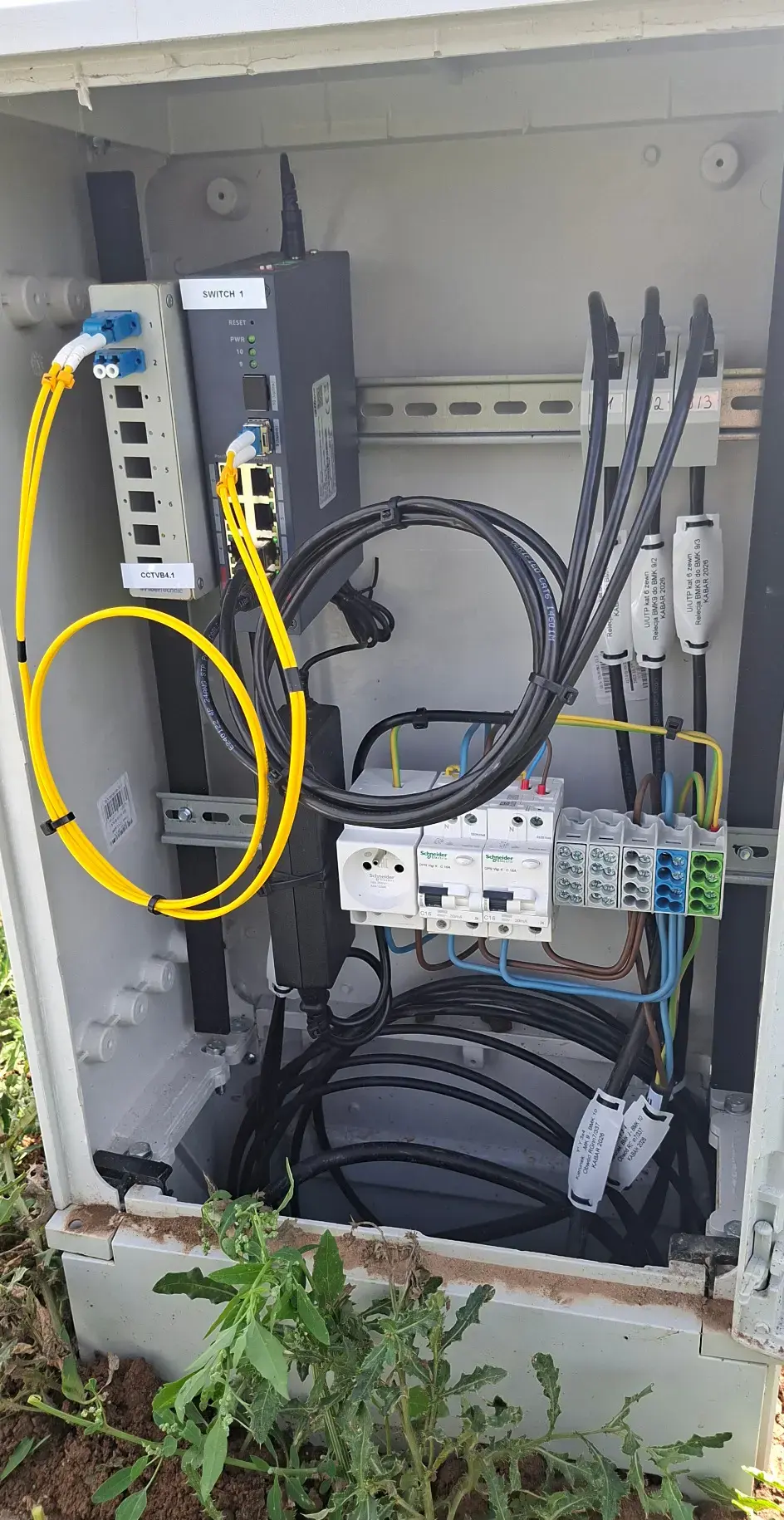 Wnętrze terenowej szafy CCTV ze switchem i połączeniami światłowodowymi